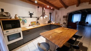 Una cocina con una isla grande, horno empotrado y pared de piedra.