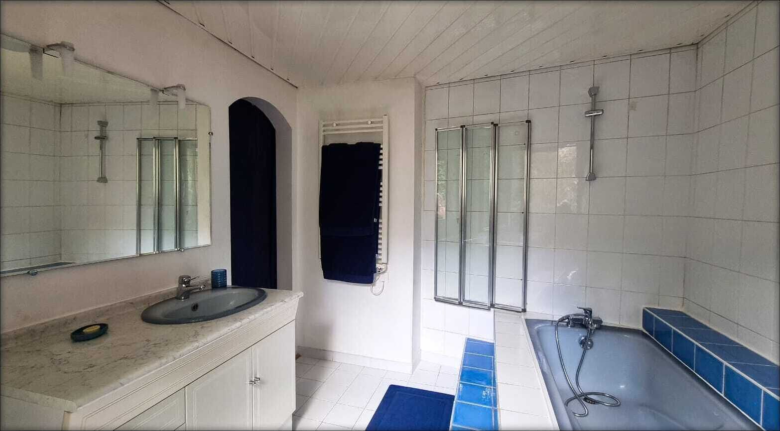 Une salle de bain avec un lavabo, un miroir, une douche et des murs carrelés.