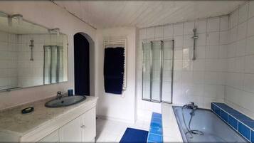 Une salle de bain avec un lavabo, un miroir, une douche et des murs carrelés.