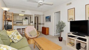 A compact living space with a kitchenette, a dining area, a seating area with a sofa and a chair, a television, and a potted plant. - Bonaire 404 2 Bedroom Condo by RedAwning (Ocean City)