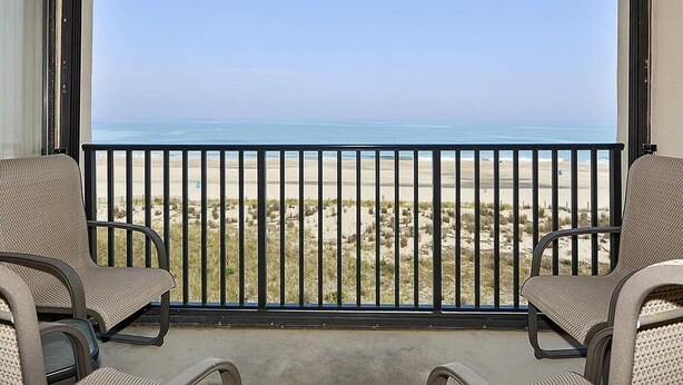 A balcony with a view of the beach, two chairs, and a railing. - Bonaire 404 2 Bedroom Condo by RedAwning (Ocean City)