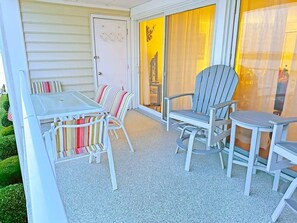 A covered patio with a table and chairs, a sliding glass door, and a view of the interior. - Thunder Island 157d 2 Bedroom Condo by RedAwning (Ocean City)