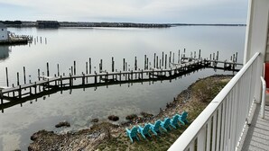A view of a calm lake with a wooden dock extending into the water, surrounded by a grassy area with blue chairs. - Thunder Island 157d 2 Bedroom Condo by RedAwning (Ocean City)