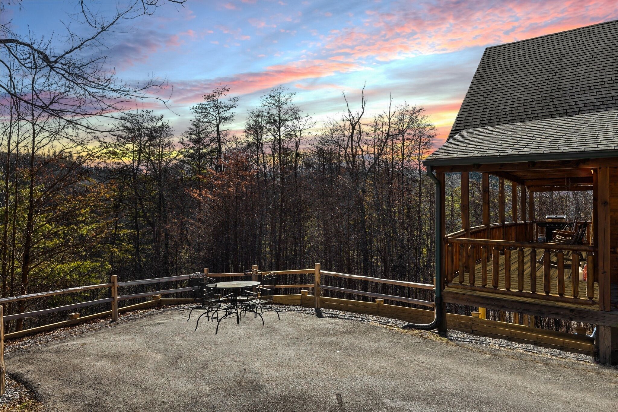 Une cabane en bois dotée d’une terrasse et d’une table de pique-nique, située dans une zone boisée.