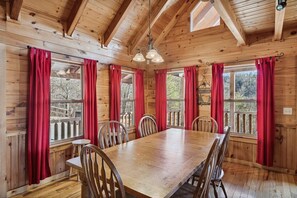 A wooden cabin with a large dining table, red curtains, and multiple windows. - Peace Of Mind 3 Bedroom Cabin by RedAwning (Sevierville)