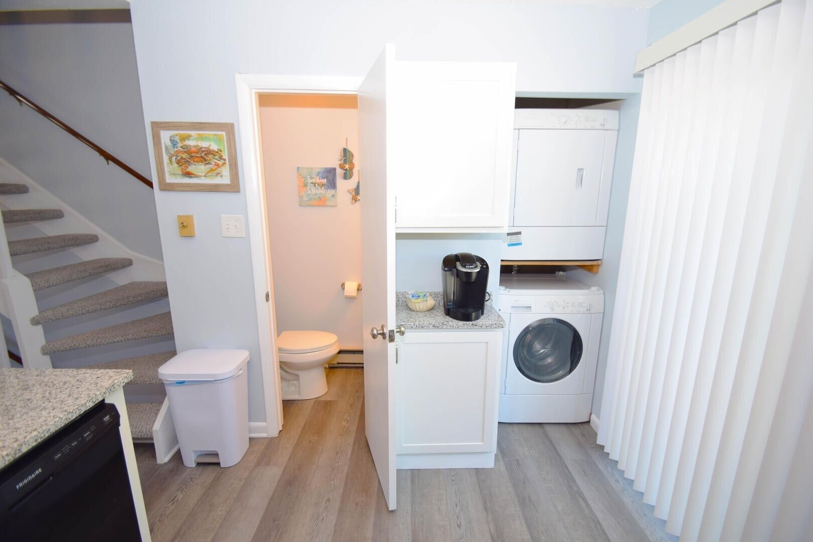 A compact kitchen with a washing machine, a coffee maker, and a small countertop.