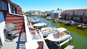 A marina with boats docked, a wooden deck, and residential buildings in the background. - Harbour Bay 34 2 Bedroom Townhouse by RedAwning (Ocean City)