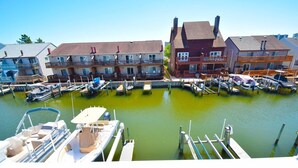 A marina with docked boats, a wooden pier, and multi-story buildings with balconies. - Harbour Bay 34 2 Bedroom Townhouse by RedAwning (Ocean City)