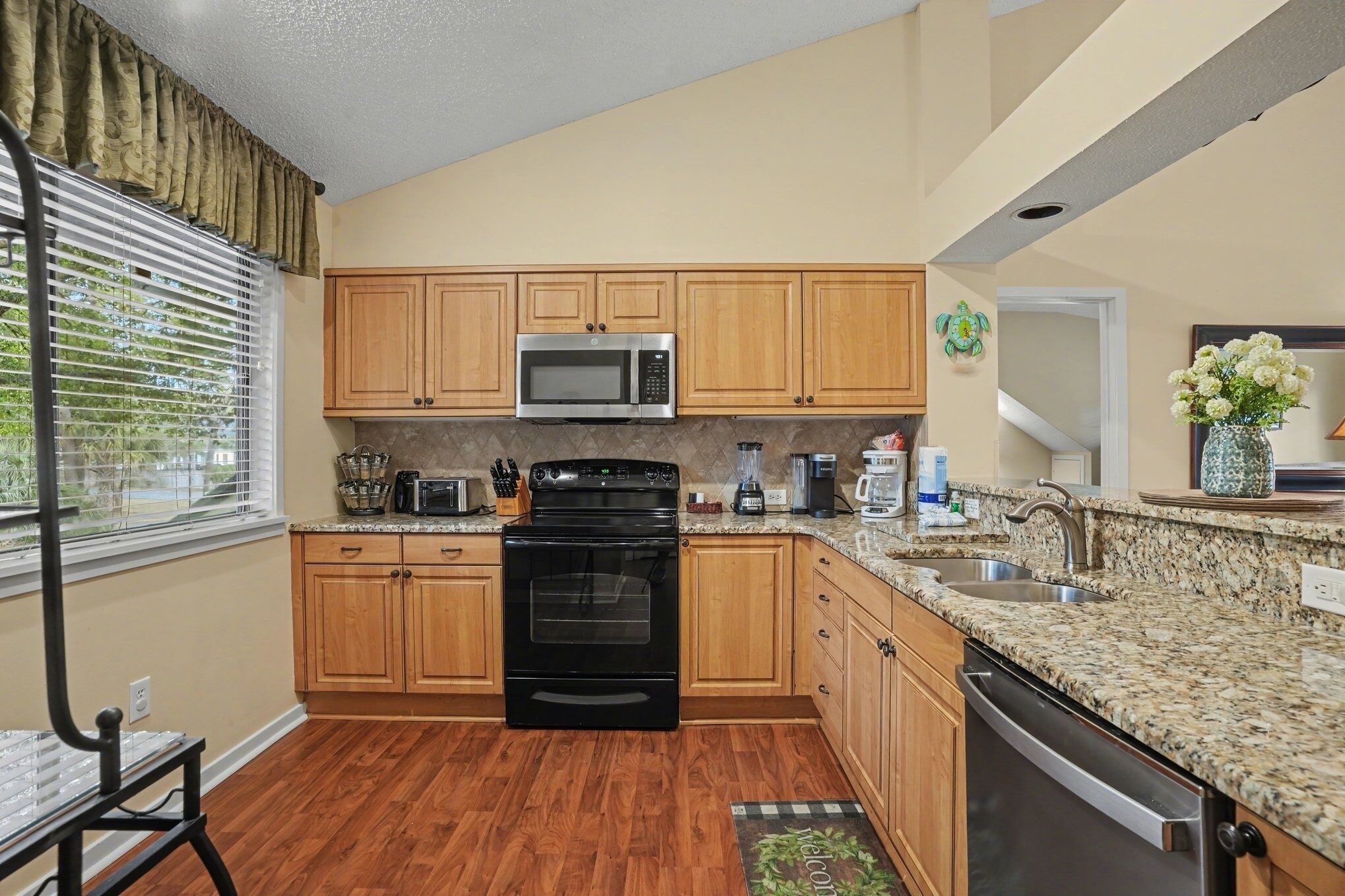 A kitchen with wooden cabinets, a black stove, a microwave, granite countertops, and a dishwasher.