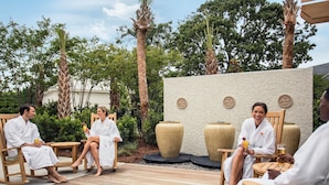 A group of people in white robes seated on wooden chairs on a wooden deck, with large decorative vases and a textured wall in the background. - Updated 3 Bedroom Bathroom Villa, 13D Richmond Park Villa (Myrtle Beach)