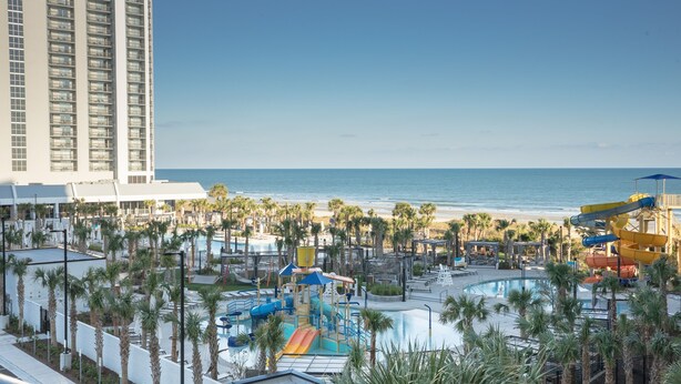 A resort with a pool area, water slides, and a beach view.