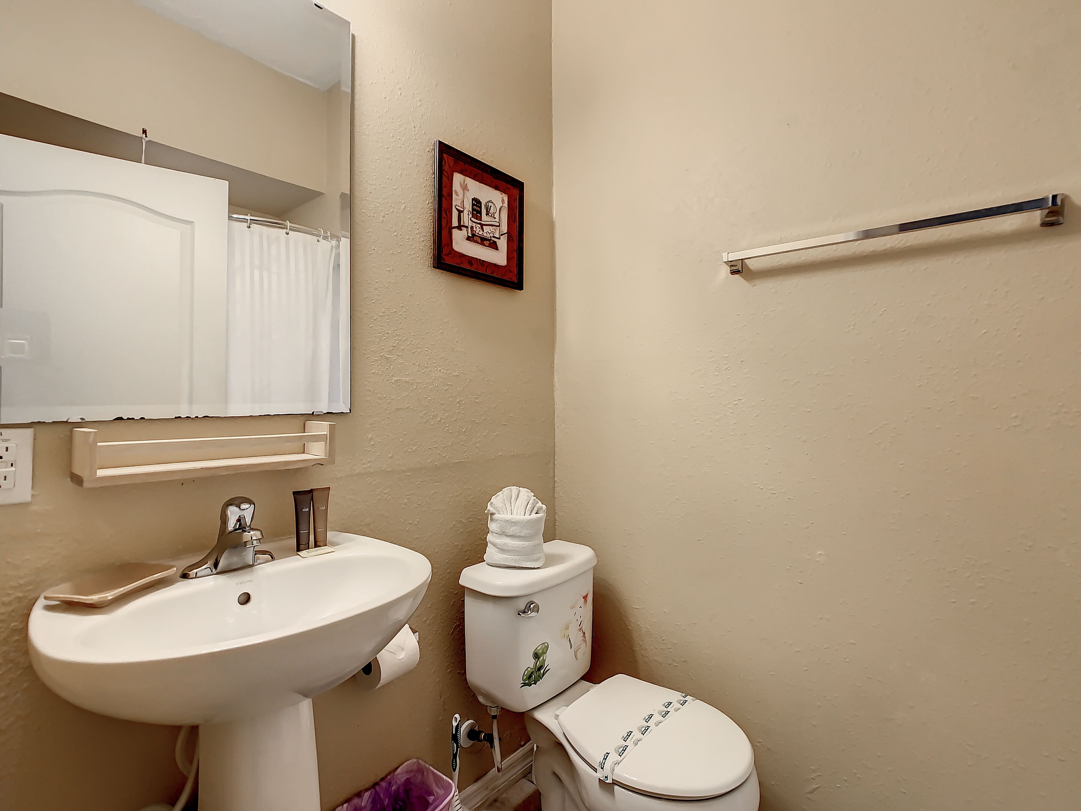 A bathroom with a sink, toilet, and a towel rack.