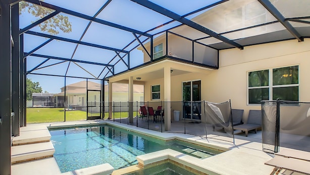 Une piscine dotée d’une enceinte en verre, d’un espace extérieur aménagé et offrant une vue sur les environs.