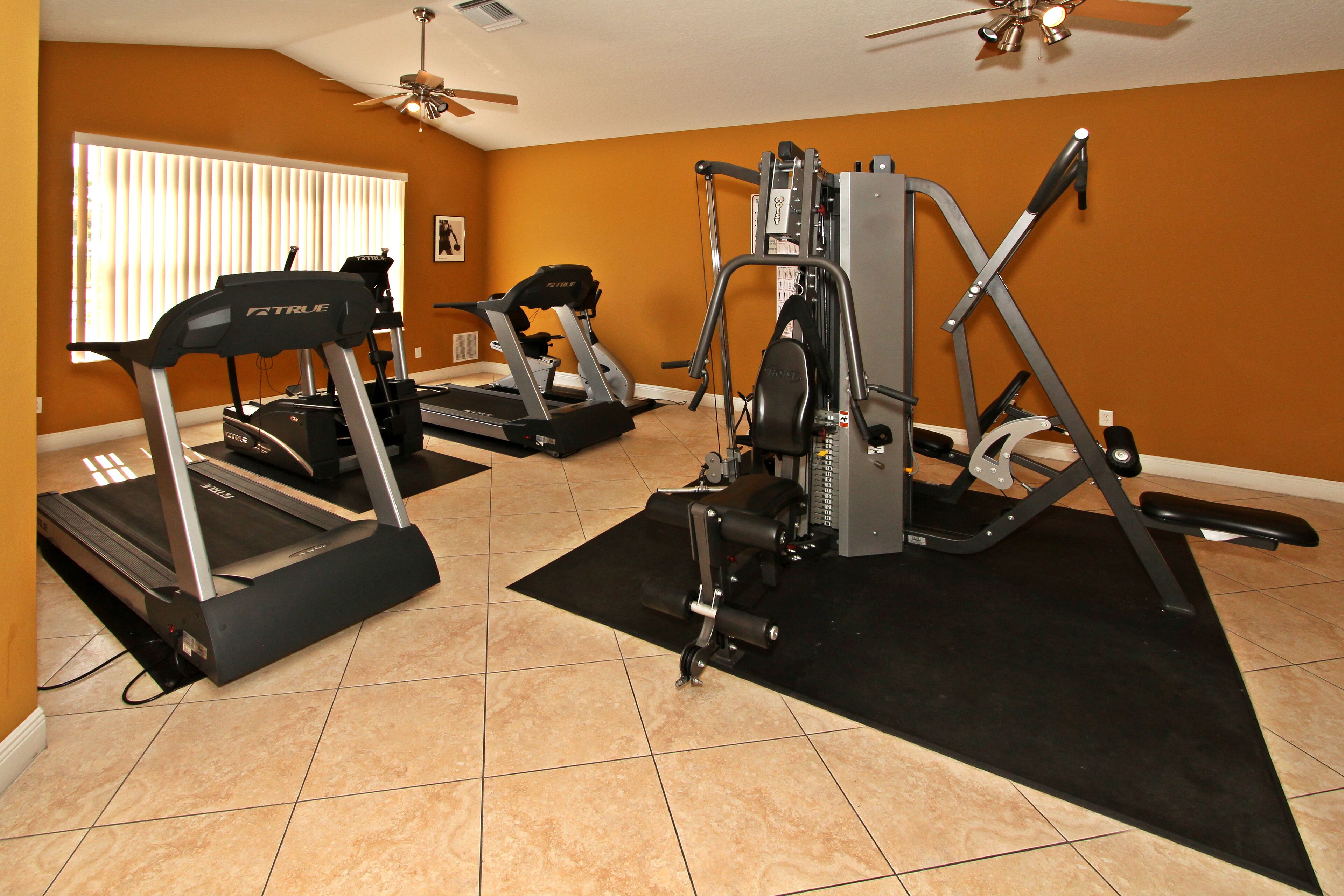 A home gym with treadmills, a weight machine, and a ceiling fan.