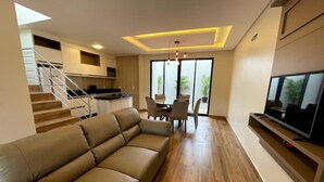 Ein modernes Wohnzimmer mit Sofa, Esstisch und Fernseher.