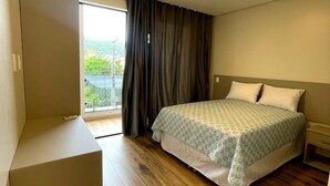 Ein Schlafzimmer mit Bett, Schrank und Blick auf Grünfläche.