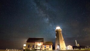 A lighthouse at night with a clear view of the Milky Way.
