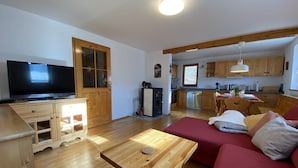A living room with a TV, wooden furniture, a sofa, and a kitchen in the background. - Quiet Family sized House in a small village (Radovljica)