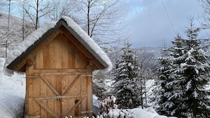 A wooden cabin with a snow-covered roof, surrounded by snow-laden trees. - Quiet Family sized House in a small village (Radovljica)