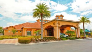 A large, single-story building with a red-tiled roof and a central entrance with a covered porch. - Luxury 4 bedroom 3 bath pool Home 283 (Kissimmee)