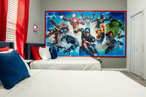 Une chambre à coucher avec un lit, des oreillers, une fresque murale représentant des super-héros et une fenêtre avec des stores.