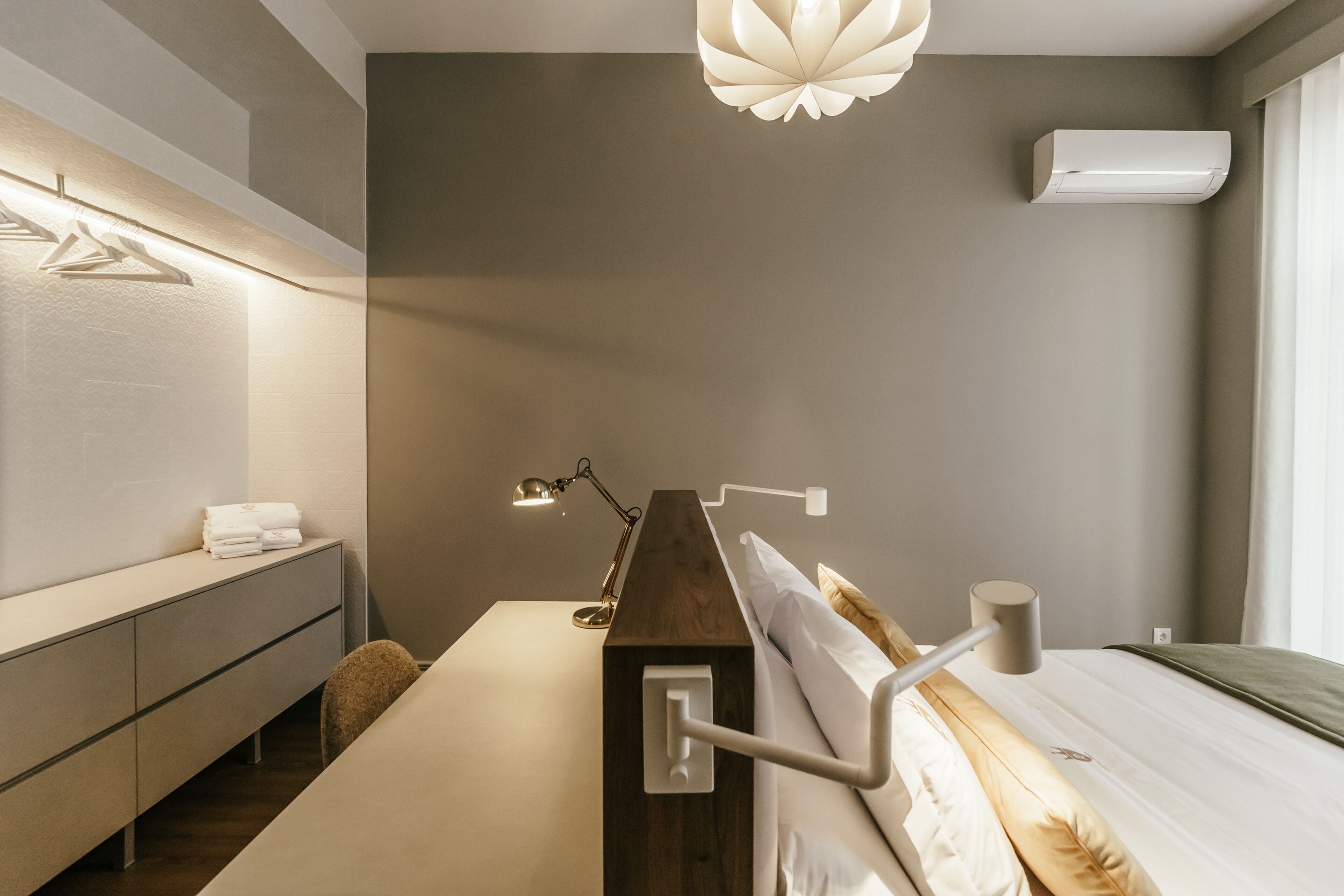 Una camera da letto moderna con una testiera in legno, un comodino, una lampada e un lampadario.