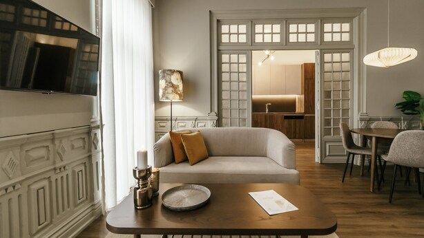 A modern living room with a sofa, a coffee table, a TV, and a dining area with chairs and a table.