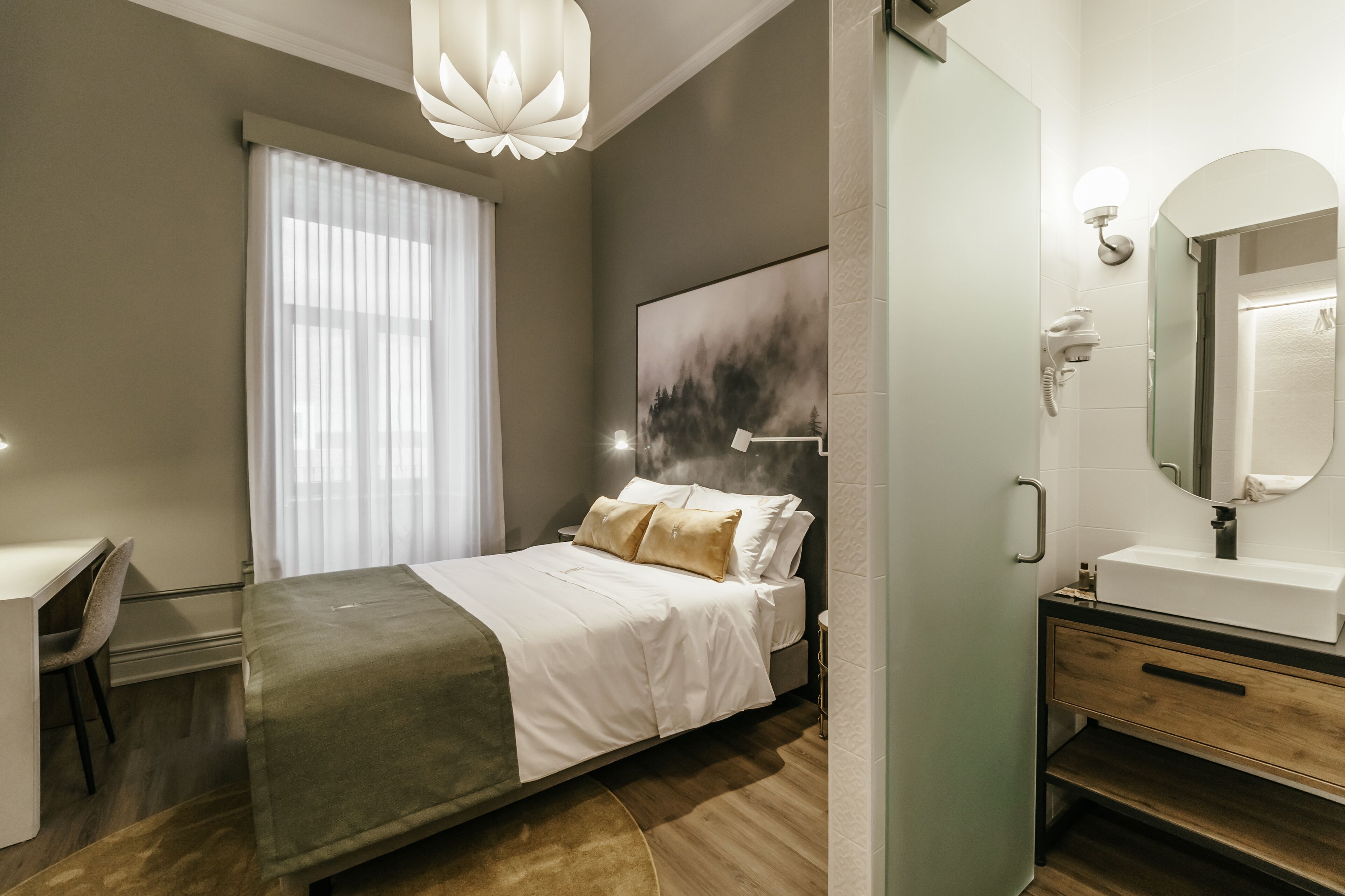 Een moderne slaapkamer met een bed, nachtkastje en een groot raam met gordijnen.