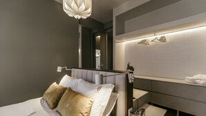 A modern hotel room with a bed, bedside table, and a mirror.