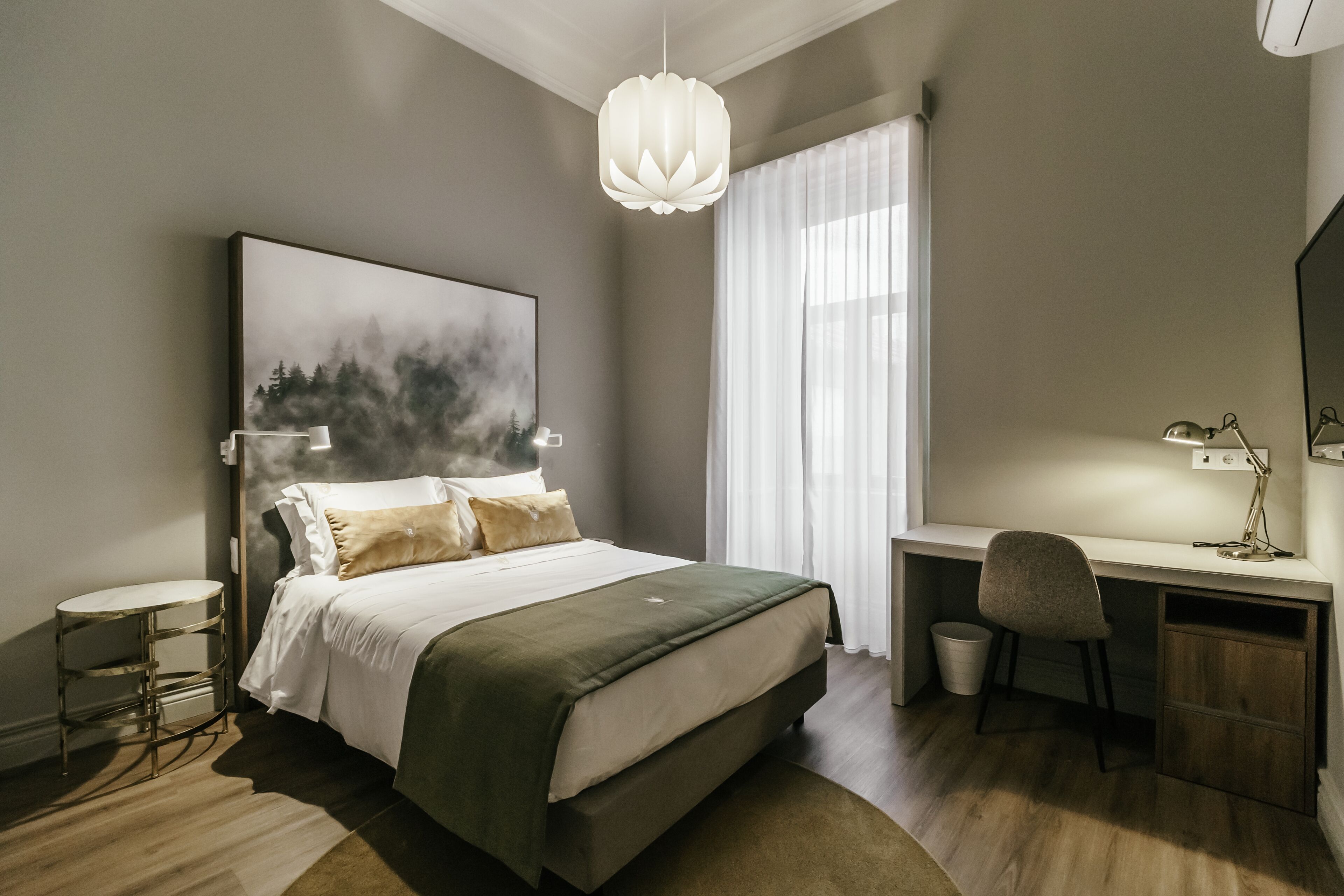 A modern bedroom with a large bed, a desk, and a chair.