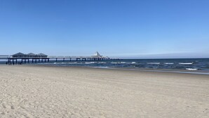 A beach with a pier extending into the ocean, featuring a gazebo and a triangular structure. - Vacation home Fischerhuus on Usedom with sauna, fireplace and private garden (Zirchow)