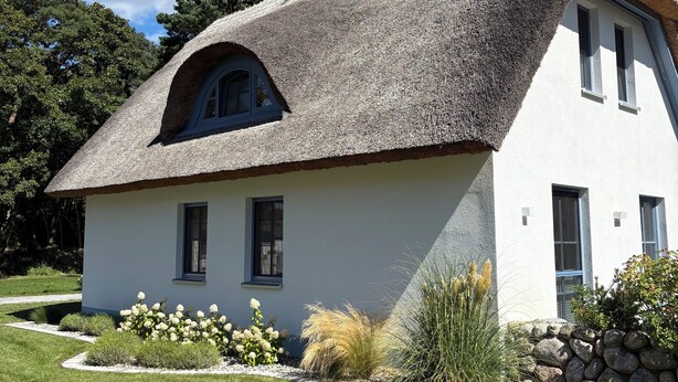 A house with a thatched roof, white walls, and a stone foundation. - Vacation home Fischerhuus on Usedom with sauna, fireplace and private garden (Zirchow)