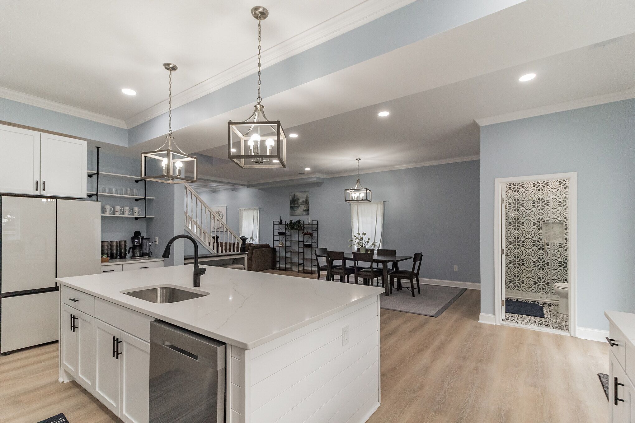 A modern kitchen with white cabinetry, a large island, and pendant lighting.