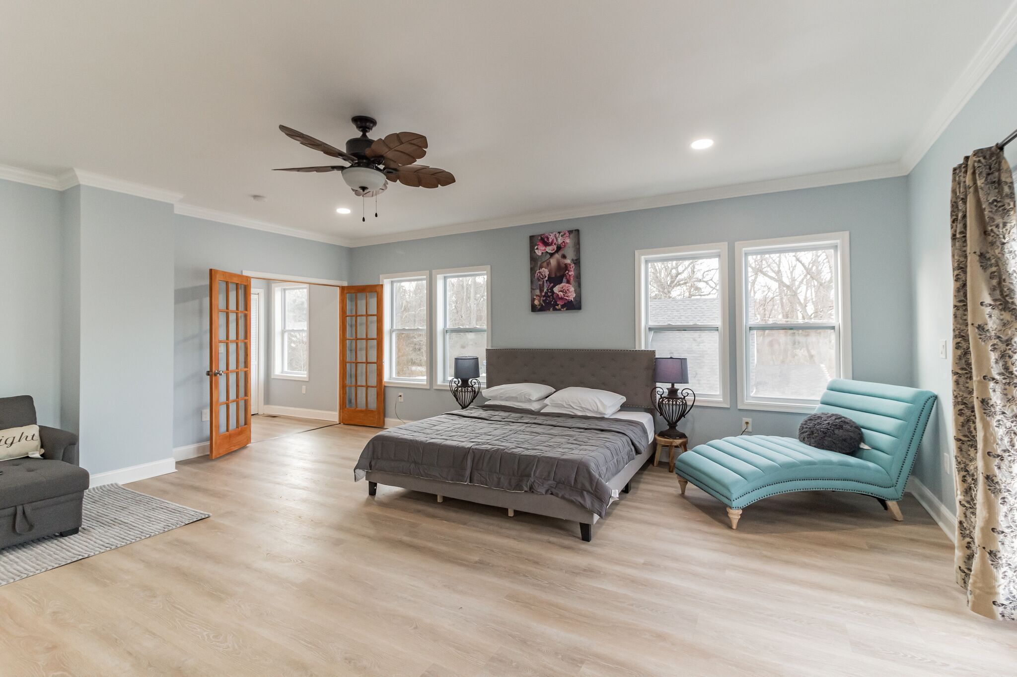 A bedroom with a bed, a chair, a ceiling fan, and a window.