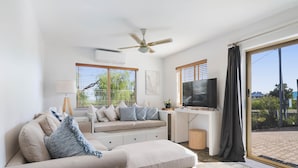 A modern living room with a sofa, TV, and a ceiling fan.
