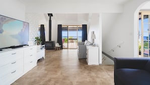 A modern living room with a flat-screen TV, white cabinetry, a fireplace, and a view to a balcony.