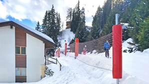 A snow-covered outdoor area with a building, a fence, and a snowy mountain in the background. - Chalet, wifi, 200m from resort center, view mountain, balcony, fireplace or stove, tv, ski locker (Les Collons)