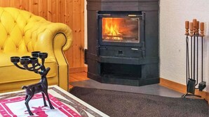 A cozy living room with a yellow sofa, a black wood-burning stove, and a decorative candle holder. - Chalet, wifi, 200m from resort center, view mountain, balcony, fireplace or stove, tv, ski locker (Les Collons)