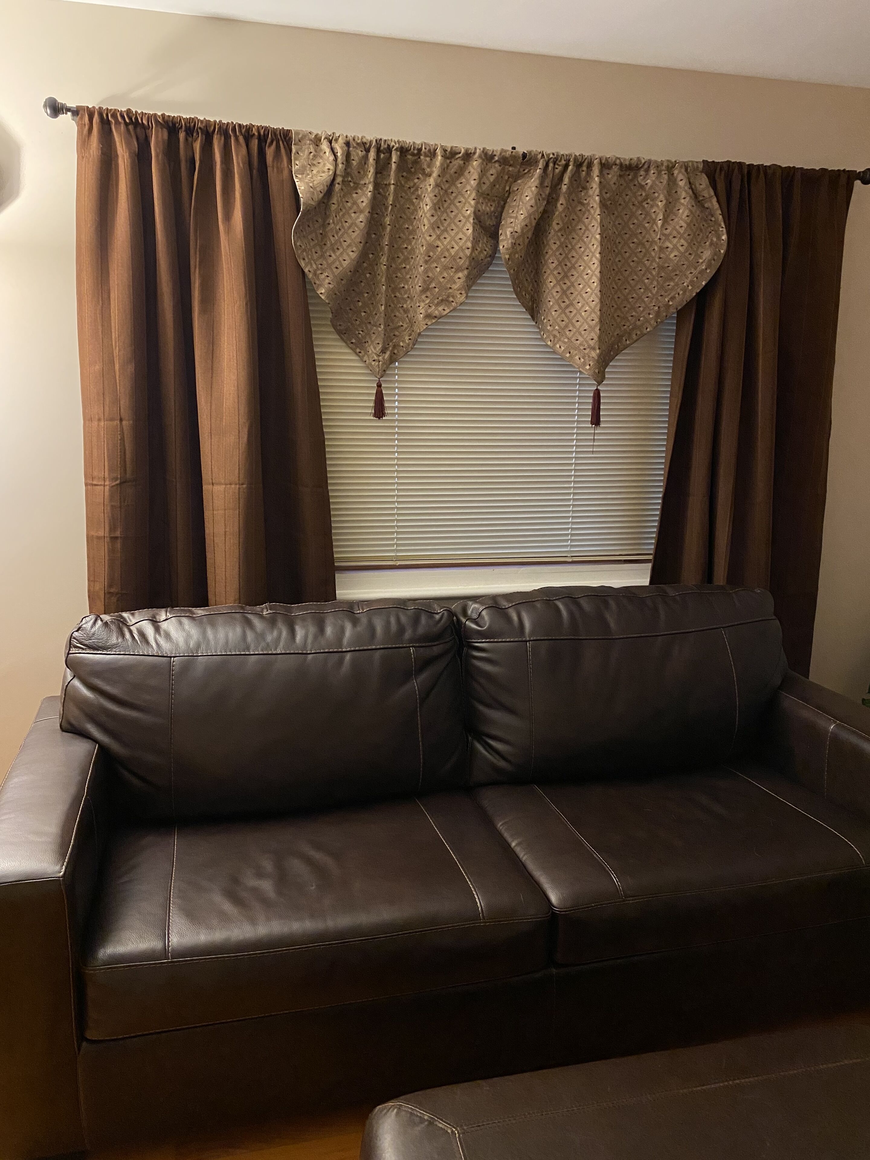 A brown leather sofa with a window in the background.