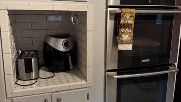 Una cocina con horno empotrado, cafetera y tostadora.