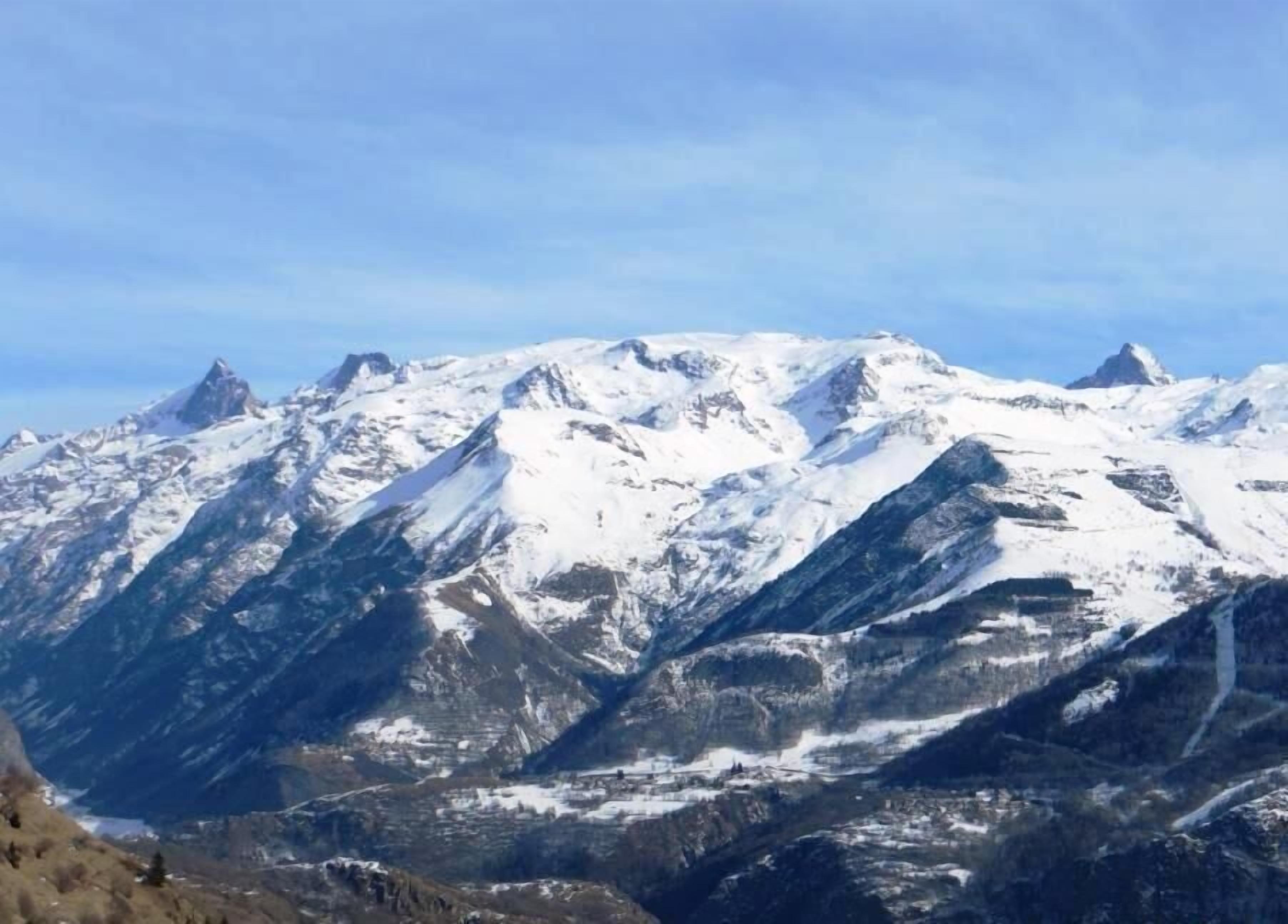 Ein verschneites Gebirge unter blauem Himmel.