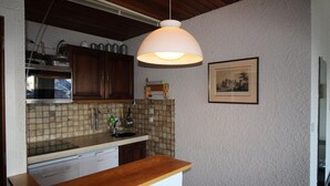 A kitchen with wooden cabinets, a tiled backsplash, a wooden countertop, a hanging light fixture, and a framed picture on the wall. - At the foot of shops, 2nd floor, view panoramic, balcony, tv, ski locker, 55m², Auris en Oisans (Auris)
