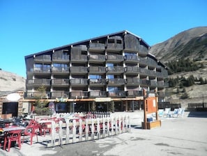 A multi-story hotel with balconies, outdoor seating, and a mountainous backdrop.