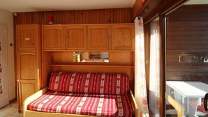 A compact room with a bed, wooden cabinets, and a window. - Ski-in/ski-out & foot of the slopes, 2nd floor, balcony, tv, 23m², Auris en Oisans (Auris)