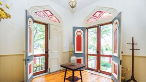 Une pièce avec un plancher en bois, une table sur laquelle est posé un vase, et deux portes avec des moulures rouges et blanches.
