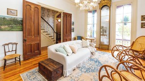 Un salon spacieux avec un canapé blanc, des chaises en bois, une commode en bois et une grande fenêtre donnant sur un beau paysage.
