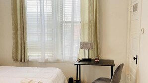 Una habitación de hotel con una cama, un escritorio, una silla y una ventana con cortinas.