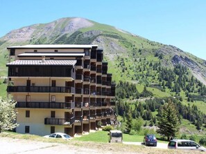 Hotel de vários andares com varandas, localizado em área montanhosa com vista desobstruída da paisagem circundante.