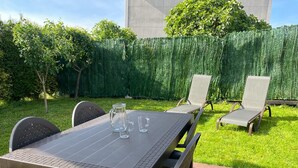 Une terrasse avec une table et des chaises, une carafe et deux verres.