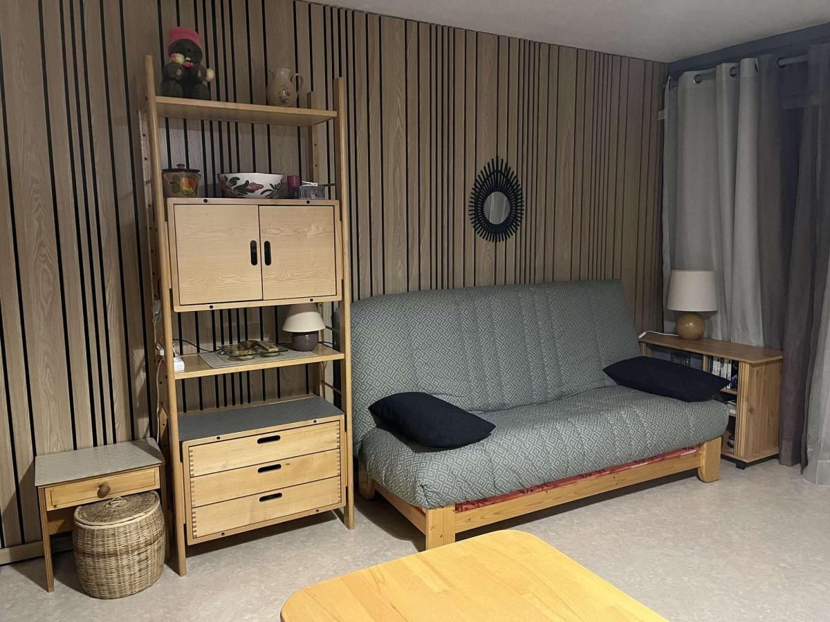 A room with a wooden sofa, a wooden cabinet with drawers, a small table, and a wicker basket.